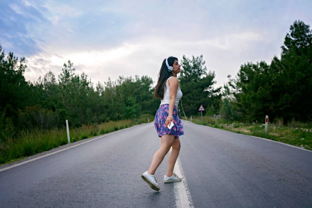 Young woman in denim and dress, standing in the forest and spread her hands wide. Relaxation concepts
