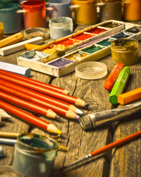 istock Tools for the artist. Inspiration to create. Objects for drawing. Paint, crayons, pencils on a wooden table. 1142471716