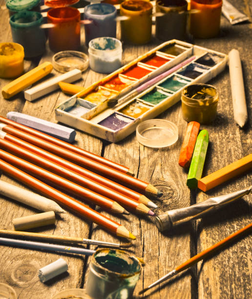 istock Tools for the artist. Inspiration to create. Objects for drawing. Paint, crayons, pencils on a wooden table. 1142471796