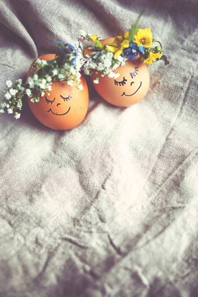 istock Natural easter eggs with funny painted face and sweet flower wreath 1142471828