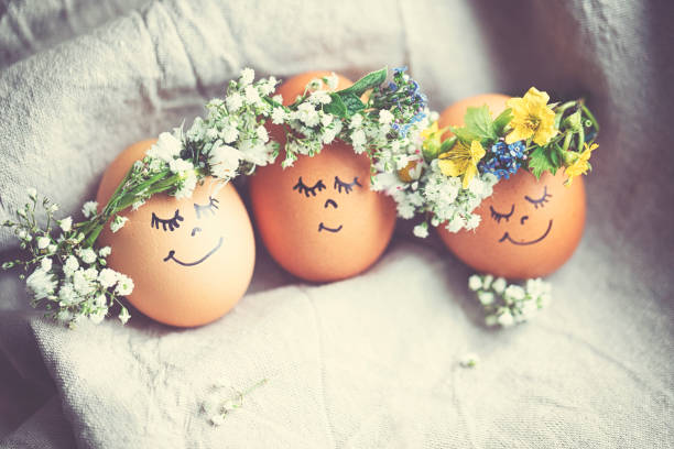 istock Natural easter eggs with funny painted face and sweet flower wreath 1142471888