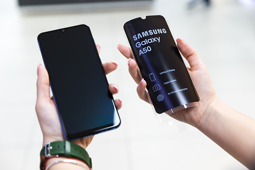 Belgrade, Serbia - April 05, 2019: New Samsung Galaxy A50 mobile cellphone is displayed in hands on isolated blurry background.