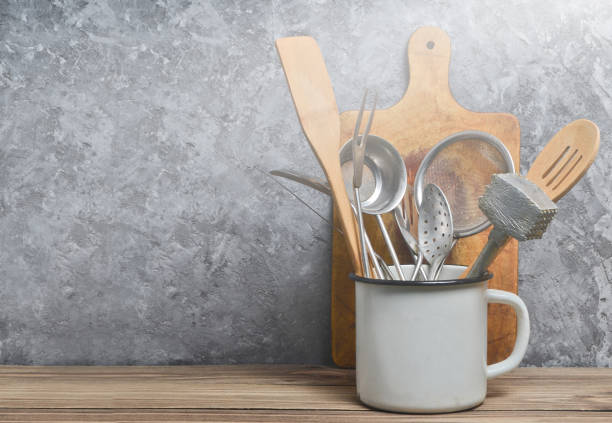 istock Kitchen tools for cooking on a wooden table on the background of a concrete wall.Copy space. Spoons, forks, wooden spatula. 1142472394