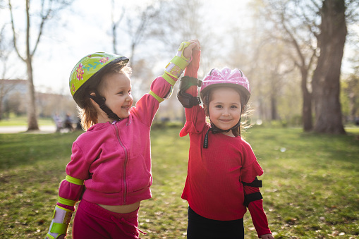Beautiful young children enjoying the day at a park on rollerblades.