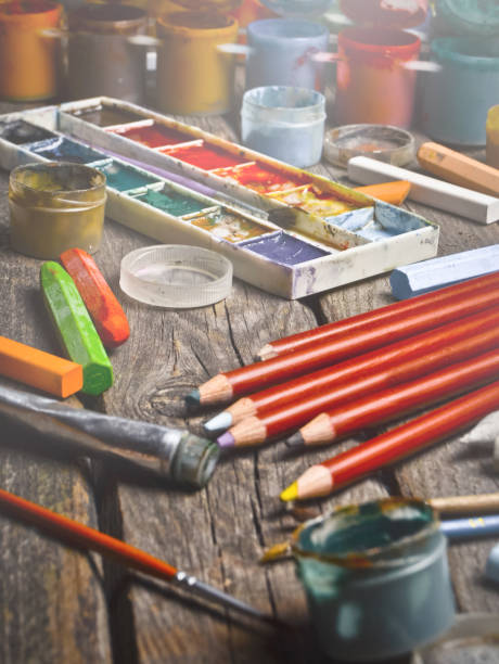 istock Tools for the artist. Inspiration to create. Objects for drawing. Paint, crayons, pencils on a wooden table. 1142473687