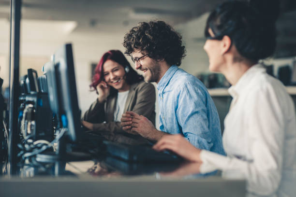 istock Beautiful young woman telephone operator with headset working on desktop computer  in  customer service call support helpline business center with teamworker in background 1142477315
