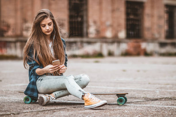 istock Female Skateboarder is Using a Mobile Phone in the Street 1142477505
