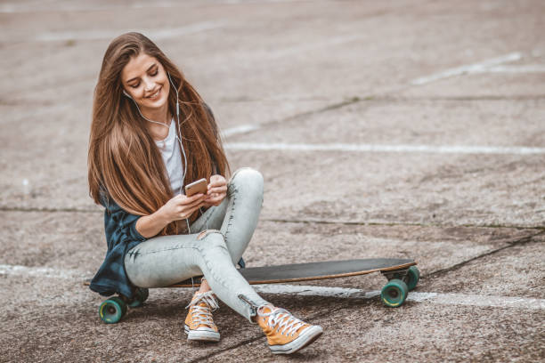 istock Female Skateboarder is Using a Mobile Phone in the Street 1142477519