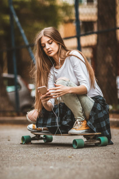 istock Female Skateboarder is Using a Mobile Phone in the Street 1142478695