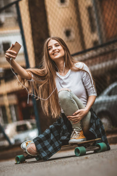 istock Female Skateboarder is Using a Mobile Phone in the Street 1142478706