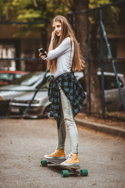 istock Female Skateboarder is Using a Mobile Phone in the Street 1142478719