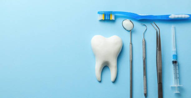 istock Tooth and dental instruments on blue background. Dental treatment. Dentist tools mirror, hook, tweezers, syringe and toothbrush. Copy space for text. 1142481500