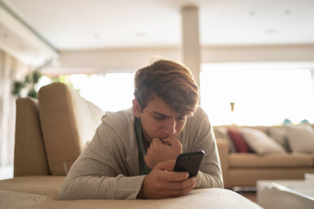 ragazzo adolescente che morde le unghie mentre usa lo smartphone - nail biting biting fingernail obsessive foto e immagini stock