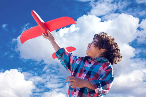 istock Young happy boy playing with red airplane outdoor 1142487211