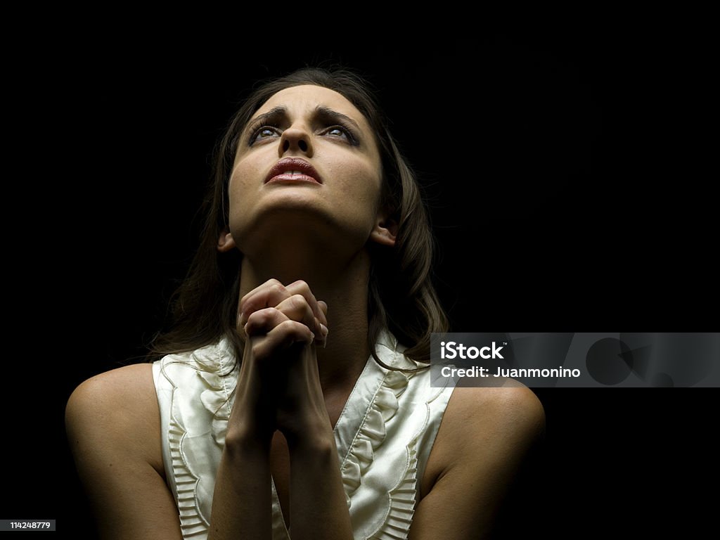Giovane donna pregare su sfondo nero - Foto stock royalty-free di Abbigliamento casual