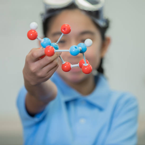 istock Junior high school girl enjoying STEM science class and showing off a molecule model 1142492924
