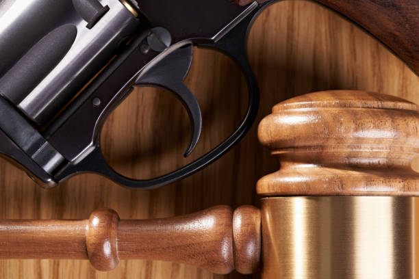 концепция законодательства о контроле над огнестрельным оружием: gavel и пистолет на деревянном столе крупным планом - gun laws стоковые фото и изображения