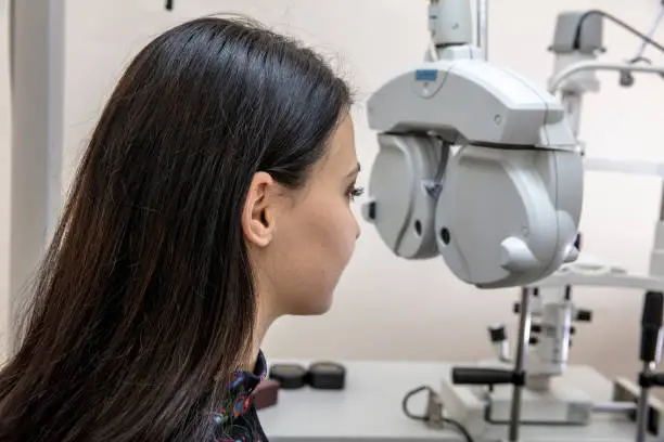 High technology concept health for eyes care - The optician ophthalmology doctor optometrist in the eyes clinic using a binocular slit-lamp to a young woman for an eye control.