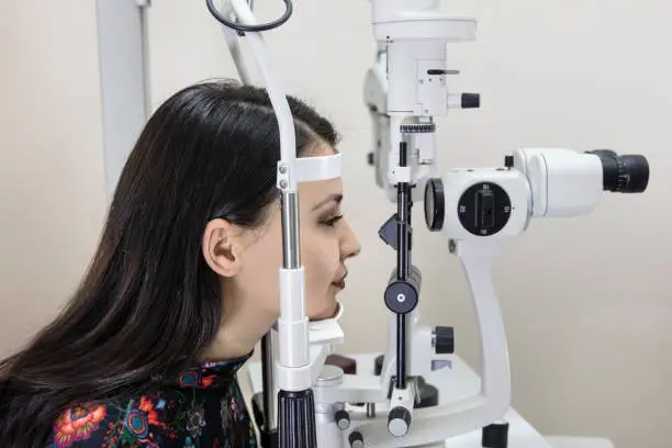 High technology concept health for eyes care - The optician ophthalmology doctor optometrist in the eyes clinic using a binocular slit-lamp to a young woman for an eye control.
