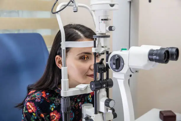 High technology concept health for eyes care - The optician ophthalmology doctor optometrist in the eyes clinic using a binocular slit-lamp to a young woman for an eye control.