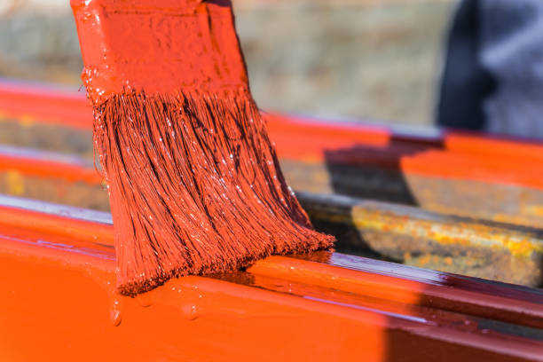istock Paint application by brush on metal structures. Protective coating of steel closed profiles with primer iron oxide red. 1142502858