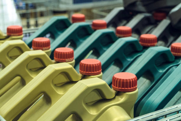 Colored plastic cans with engine oil. Rows of canisters placed on a pallet. Limited depth of field.