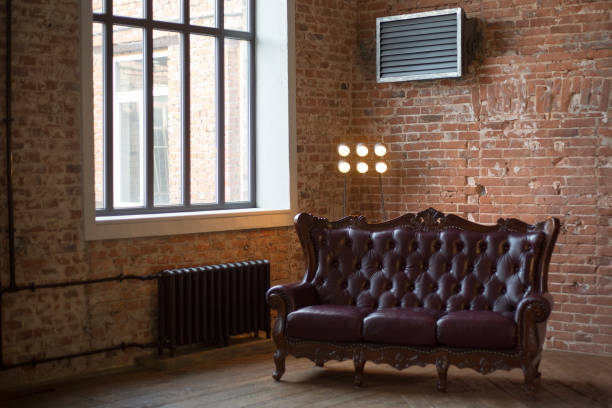 istock claret leather sofa to the loft an interior with a bright searchlight and a window. brick wall. ancient pig-iron battery 1142506356