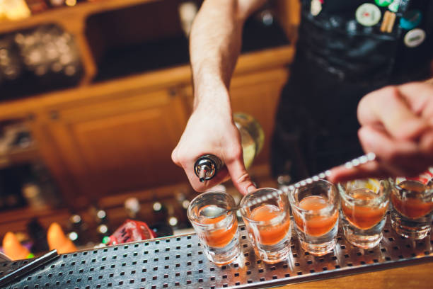 istock Bartender pouring strong alcoholic drink into small glasses on bar, shots. 1142516326