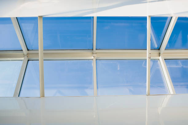 A modern open skylight mansard window in an attic room against blue sky