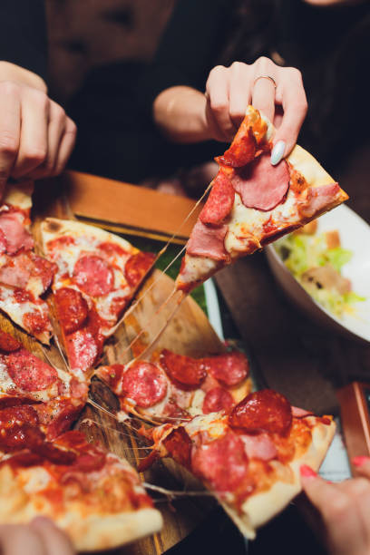 素朴な木製テーブルの上にカルボナーラのピザを手でつかみます。食品写真のコンセプト。上面図。 - pizza pizzeria friendship people ストックフォトと画像