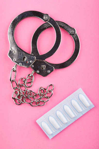 istock Handcuffs and packages with suppository on pink background 1142524481