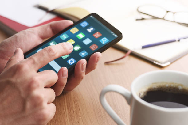 gros plan des mains mâles touchant l’écran de smartphone pour utiliser l’application à la table. - application mobile photos et images de collection