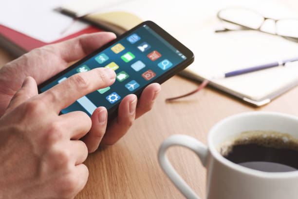 Closeup of male hands touching smartphone screen for using app at table.