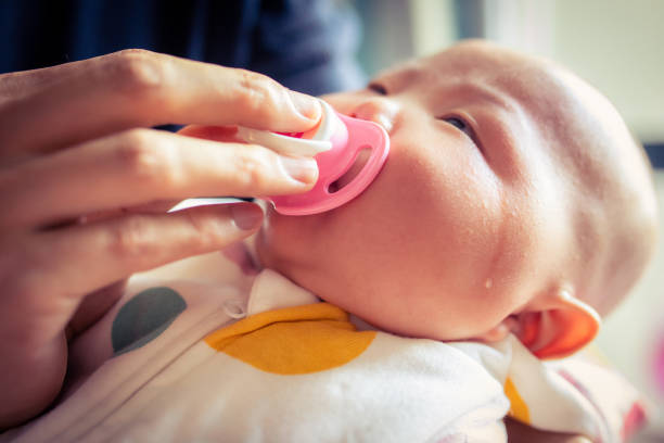 Crying little baby with Pacifier in mouth