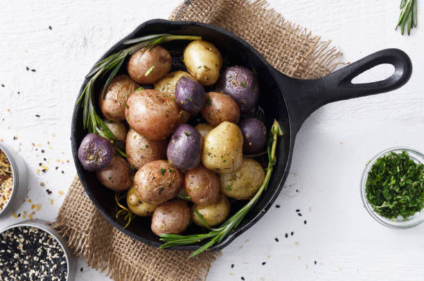 Cooked small potatoes in a skillet Cooked three colors small potatoes in a cast iron skillet on a white background prepared potato stock pictures, royalty-free photos & images