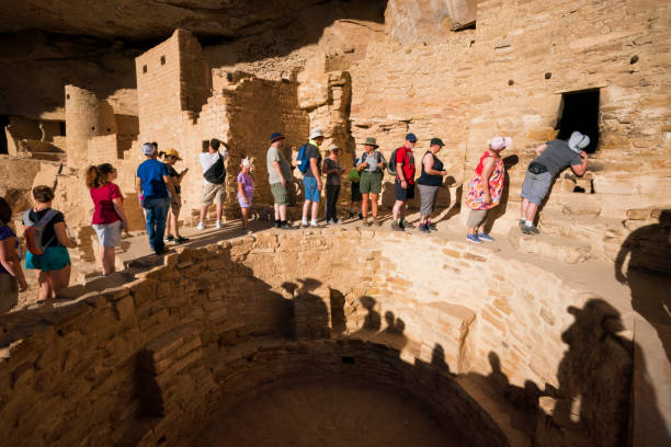 groupe de personnes se rassemblent autour d’un kiva et pair à l’intérieur d’une fenêtre d’une tour pour voir des décorations géométriques peintes sur le mur à cliff palace, une demeure de falaise habitée par les anciens puebloans (anasazi)  - ancient pueblo peoples photos et images de collection