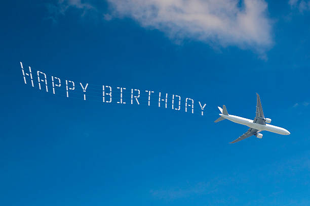 Passenger Jet Skywriting 'HAPPY BIRTHDAY' Jet towing 'HAPPY BIRTHDAY' banner across blue sky. words in the sky stock pictures, royalty-free photos & images
