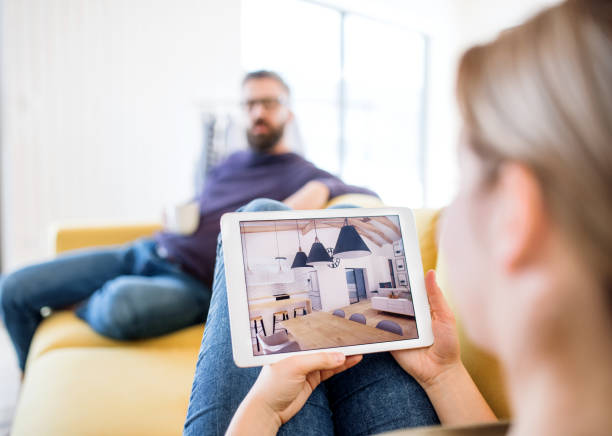 istock Young couple with tablet sitting on sofa, looking at interior design sketches. 1142548930