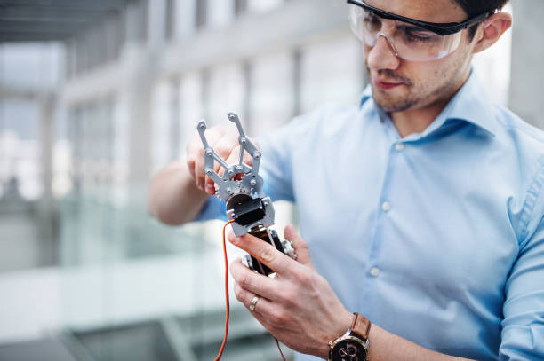istock A young businessman or scientist with robotic hand standing in office, working. 1142549392