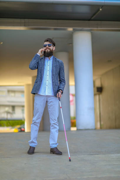 istock Blind and bearded man with a walking stick on the street 1142549432