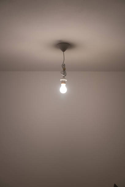 istock naked lit light bulb hanging from the ceiling of a dimly lit room 1142551536