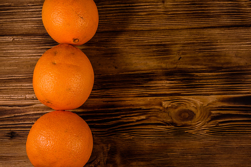 Three orange fruits on rustic wooden table. Top view