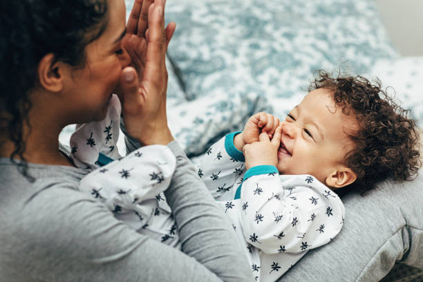 mutter hält baby auf dem schoß und spielt. glücklicher kleiner junge, der mutter anschaut. - auf dem schoß stock-fotos und bilder