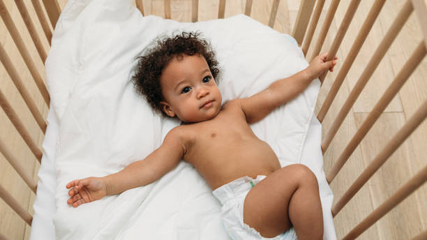 istock Curly haired baby boy lying in a crib 1142551904