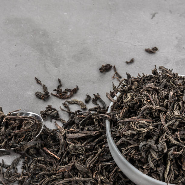 istock Dried tea in a white ceramic cup with a spoon on a gray textured background. 1142555866
