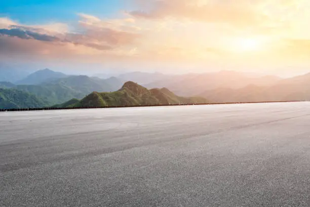 Photo of Asphalt race track ground and mountain with sunset clouds