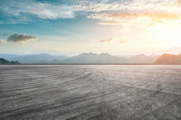 istock Asphalt race track ground and mountain with sunset clouds 1142558521