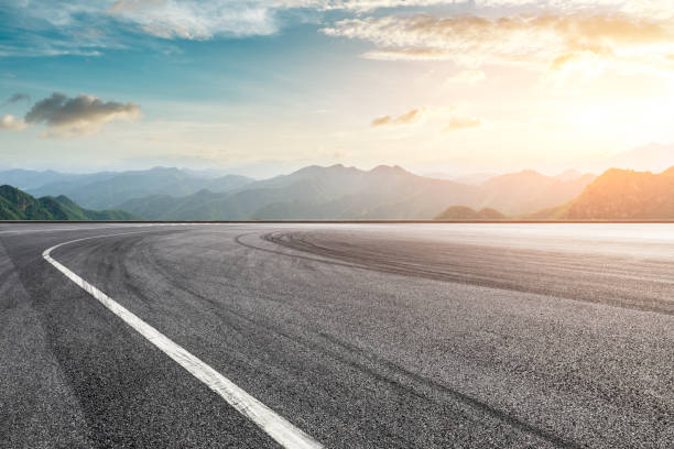 Asphalt race track ground and mountain with sunset clouds Empty asphalt race track ground and mountain with sunset clouds sports track stock pictures, royalty-free photos & images