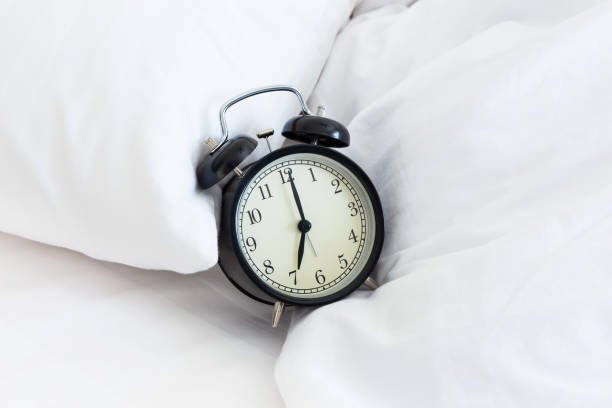 istock Vintage retro alarm clock on untidy bed 1142558750