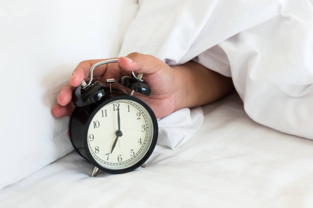 istock Man extend hand reaching to turn off alarm clock switch 1142558761